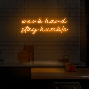 A glowing neon sign with the phrase 'Work Hard Stay Humble' in bold, vibrant colors, inspiring dedication and humility.