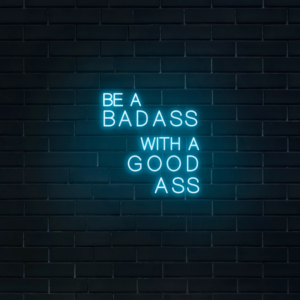 A glowing neon sign with the phrase 'Be a Badass with a Good Ass' in bold, vibrant colors, evoking confidence and attitude.