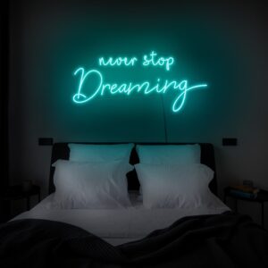 A glowing neon sign with the phrase 'Never Stop Dreaming' in vibrant colors, evoking motivation and ambition.