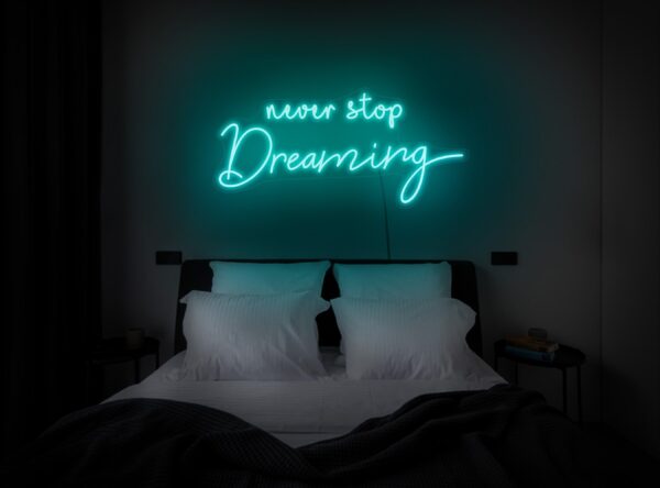 A glowing neon sign with the phrase 'Never Stop Dreaming' in vibrant colors, evoking motivation and ambition.