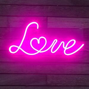 Neon sign spelling out the word 'LOVE' in cursive, glowing in a warm pink light against a dark background.